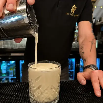 A cocktail being poured at the bar